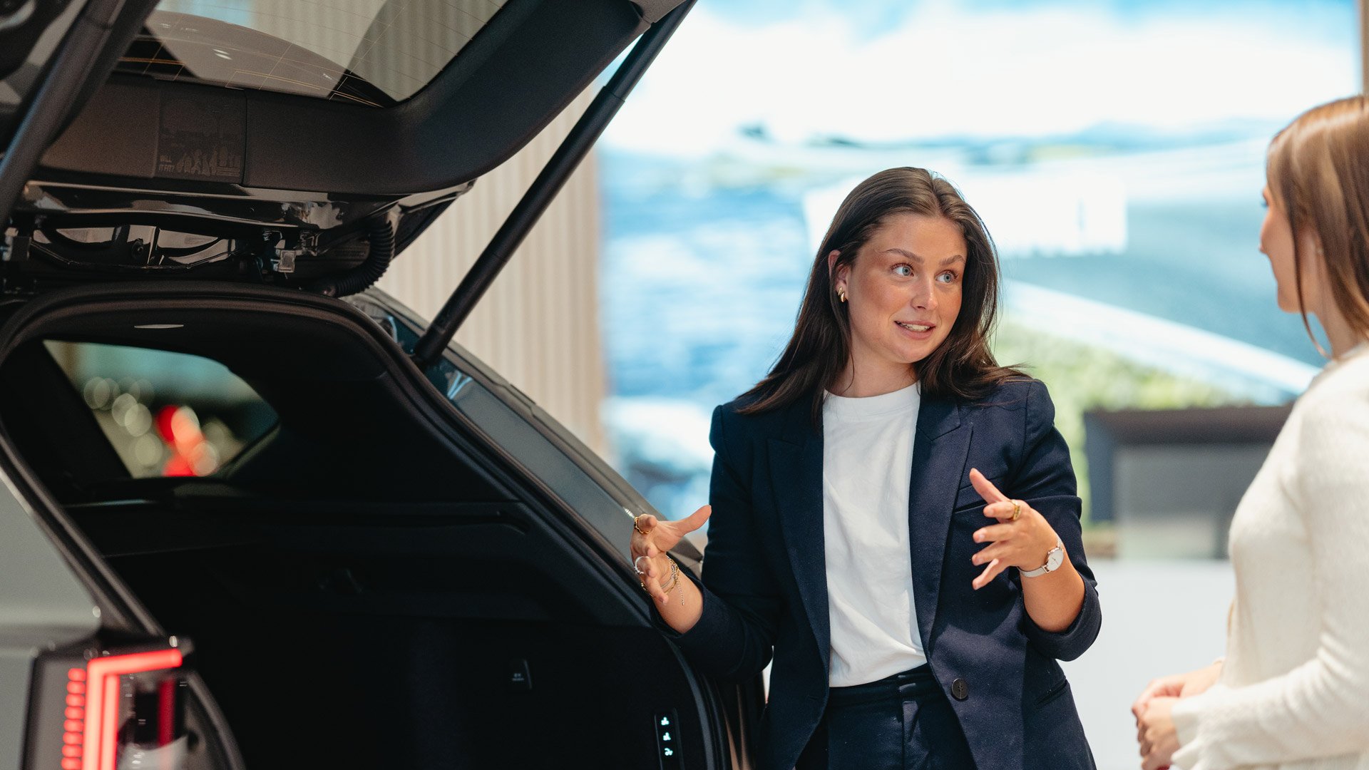 Nathalie Skoglund hos Frydenbø Bil Kokstad forklarer og viser bagasjerommet i en Volvo EX60 til en kvinnelig kunde